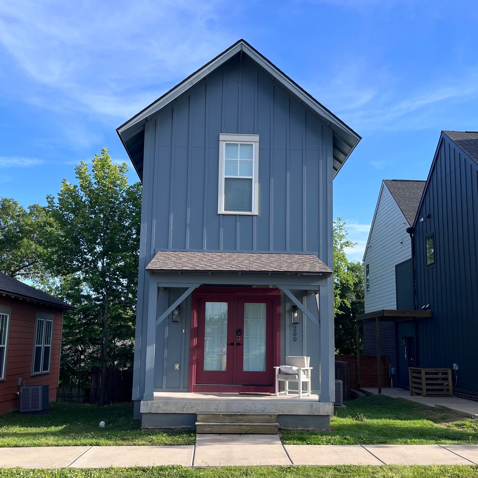 Two story blue ADU with double doors and a front porch